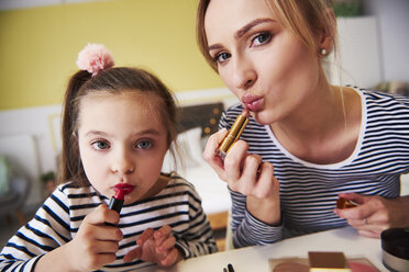Mother and daughter applying make up together, using lipstick - ABIF01201