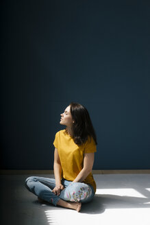 Frau im Schneidersitz im Sonnenlicht sitzend, mit geschlossenen Augen - KNSF05611