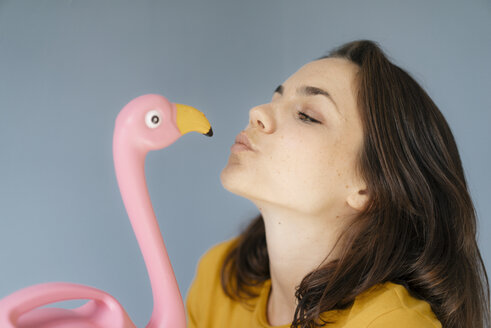 Woman kissing pink flamingo figure - KNSF05617