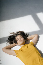 Woman lying on floor, relaxing in the sunlight - KNSF05631