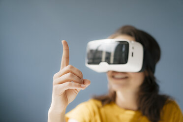 Woman wearing VR glasses, watching raised finger - KNSF05635