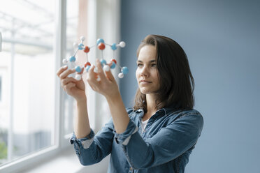 Female scientist studying molecule model, looking for solutions - KNSF05644