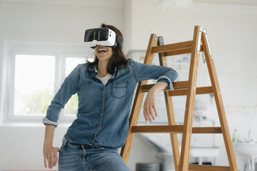 Frau mit VR-Brille, die sich auf eine Leiter stützt - KNSF05654