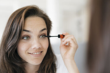 Pretty woman applying make up, using mascara - KNSF05668
