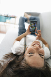 Woman lying on couch, using smartphone - KNSF05672