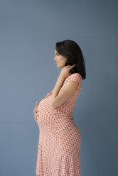 Frau tut so, als sei sie schwanger, berührt den Bauch, Seitenansicht - KNSF05676