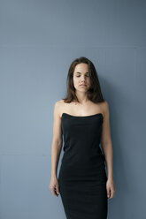 Hübsche Frau im Kleid, stehend vor blauem Hintergrund - KNSF05711