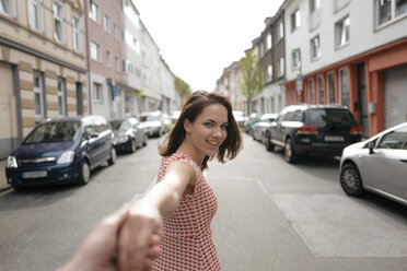 Woman walking in street, holding hand of a man - KNSF05715