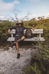 Wanderer in voller Länge mit Rucksack und Strohhut auf einer Bank im Wilsons Promontory National Park sitzend - CAVF60693