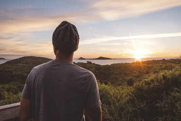 Man wearing knit hat looking at view against sky during sunset - CAVF60697