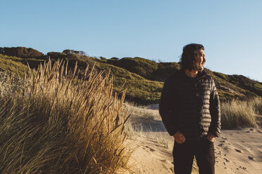 Man looking away while standing at lakeshore against clear blue sky during sunset - CAVF60703