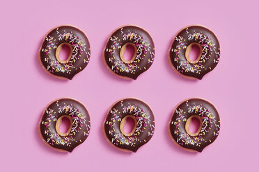 Overhead-Ansicht von Schokolade Donuts mit Streuseln auf rosa Hintergrund angeordnet - CAVF60718