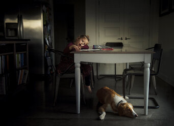 Mädchen, das am Esstisch malt, während der Hund zu Hause auf dem Boden liegt - CAVF60784
