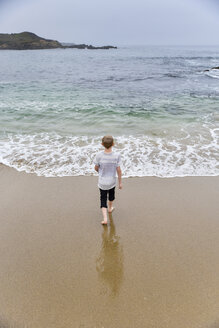 Rückansicht eines Jungen, der am Strand gegen den klaren Himmel läuft - CAVF60795