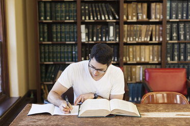 Selbstbewusster männlicher Student beim Lernen in der Bibliothek - CAVF60813