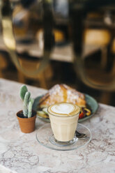 Close-up of fresh breakfast served by potted plant on table at cafe - CAVF60840