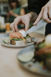 Cropped hands of man cutting boiled egg in plate with kitchen knife - CAVF60841