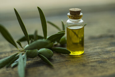 Close-up of almond plant with oil in bottle on wooden table - CAVF60843