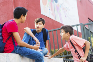 Niedriger Blickwinkel auf Freunde, die sich vor einem Schulgebäude unterhalten - CAVF60856