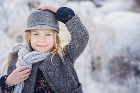 Porträt eines niedlichen Mädchens in warmer Kleidung auf einem Feld im Winter - CAVF60885