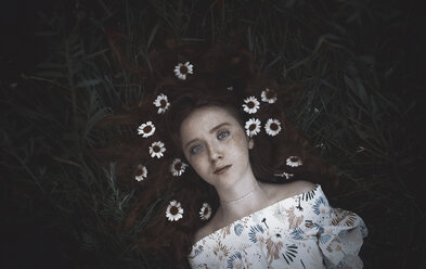 High angle portrait of teenage girl with chamomiles lying on grassy field - CAVF60897