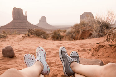 Tiefschnitt von Freunden, die im Monument Valley Tribal Park auf Sand sitzen, gegen den Himmel - CAVF60915