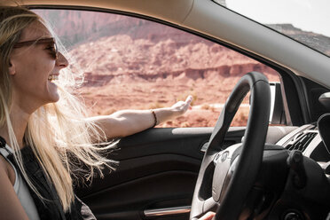 Glückliche Frau mit Sonnenbrille gestikuliert beim Autofahren im Monument Valley Tribal Park - CAVF60924