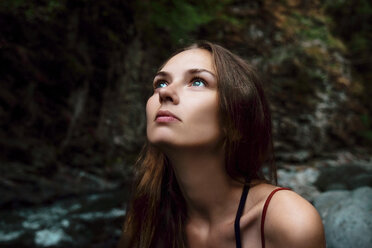 Close-up of thoughtful woman looking away while sitting in forest - CAVF60948