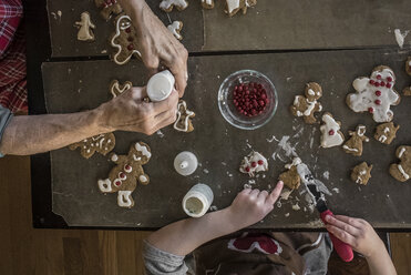 Abgeschnittene Hände von Großmutter und Enkelin, die zu Hause Lebkuchenmännchen machen - CAVF60967