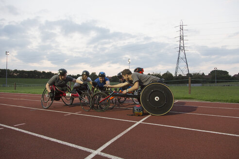 Querschnittsgelähmte Athleten kauern auf einer Sportbahn und trainieren für ein Rollstuhlrennen - CAIF22603