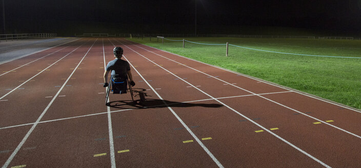 Querschnittsgelähmter trainiert nachts auf einer Sportbahn für ein Rollstuhlrennen - CAIF22606