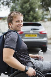 Portrait confident young female university student in wheelchair in parking lot - CAIF22607