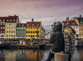 Couple enjoying view of canal and colorful buildings, Copenhagen, Denmark - CAIF22619