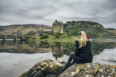 Frau genießt den Blick auf eine abgelegene Burg am Wasser, Schottland - CAIF22627