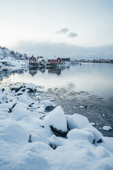 Malerische, verschneite Aussicht auf ein Fischerdorf am Wasser, Reine, Lofoten Inseln, Norwegen - CAIF22631