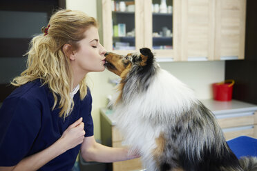 Junge Frau und Hund küssen sich in der Tierarztpraxis - ABIF01216