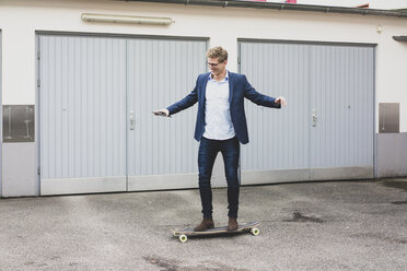 Young businessman riding skateboard at garage door - MOEF02102