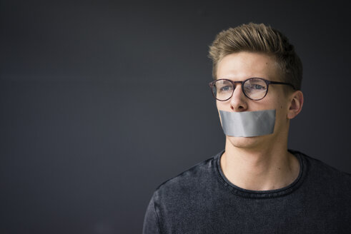 Portrait of young man with taped mouth - MOEF02110