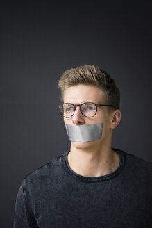 Portrait of young man with taped mouth - MOEF02111