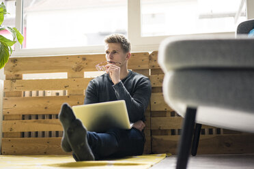 Young man sitting on the floor using laptop - MOEF02149