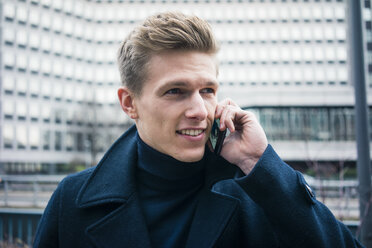 Portrait of smiling young man talking on cell phone in the city - MOEF02150