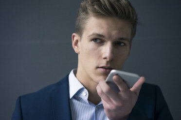 Porträt eines jungen Geschäftsmannes mit Smartphone - MOEF02158