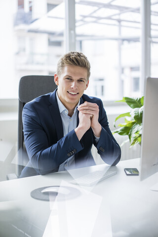 Porträt eines selbstbewussten jungen Geschäftsmannes, der am Schreibtisch im Büro sitzt, lizenzfreies Stockfoto