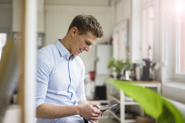 Smiling young businessman using tablet in office - MOEF02169