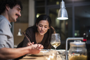 Paar isst Abendessen mit Stäbchen und trinkt Weißwein in der Wohnküche - CAIF22652