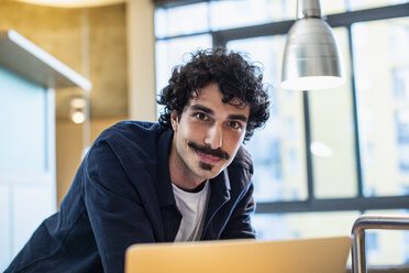 Portrait smiling man using laptop at home - CAIF22658