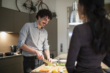 Ehepaar schneidet Gemüse und kocht Abendessen in der Wohnküche - CAIF22668