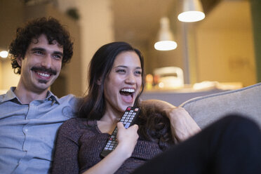 Lachendes Paar beim Fernsehen auf dem Sofa - CAIF22669