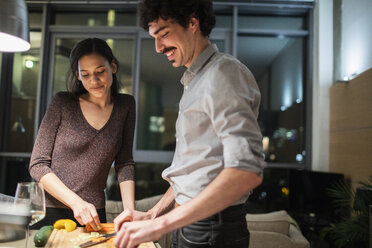 Couple cutting vegetables, cooking dinner in apartment kitchen - CAIF22670