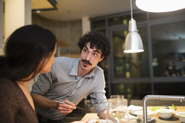 Ehepaar isst Abendessen mit Stäbchen in der Wohnküche - CAIF22672